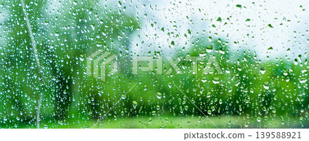 A rainy day window view. Rain drops on window. Condensed rain drop on the car glass window on a rainy day. Dew moisture condensation on wet mirror background. Fresh weather. Water raindrop bg A rainy day window view. Rain drops on window. Condensed rain drop on the car glass window on a rainy day. Dew moisture condensation on wet mirror background. Fresh weather. Water raindrop bg 139588921