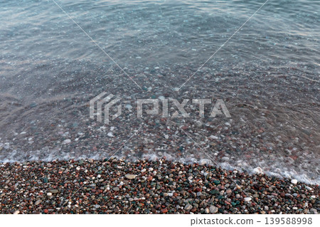 Pebble beach shoreline with gentle sea waves and clear water texture background Pebble beach shoreline with gentle sea waves and clear water texture background 139588998