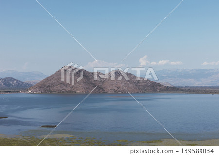 Scenic Skadar Lake panorama with rocky mountain island and calm blue water Scenic Skadar Lake panorama with rocky mountain island and calm blue water 139589034