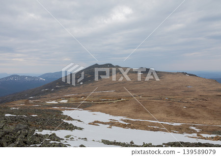 Konzhakovsky Kamen mountain plateau with melting snow under cloudy sky Konzhakovsky Kamen mountain plateau with melting snow under cloudy sky 139589079