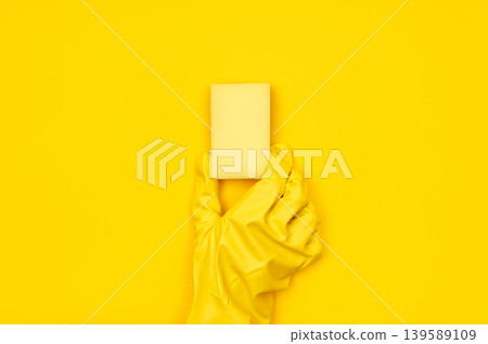 Hand in yellow cleaning glove holding yellow sponge Hand in yellow cleaning glove holding yellow sponge 139589109