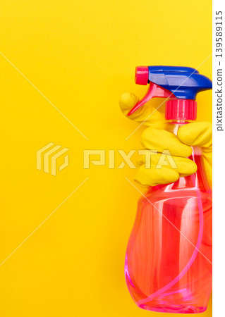 Hand in yellow glove holding cleaning spray with copy space Hand in yellow glove holding cleaning spray with copy space 139589115