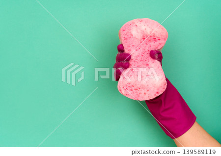 Hand in pink cleaning glove holding soapy pink sponge Hand in pink cleaning glove holding soapy pink sponge 139589119