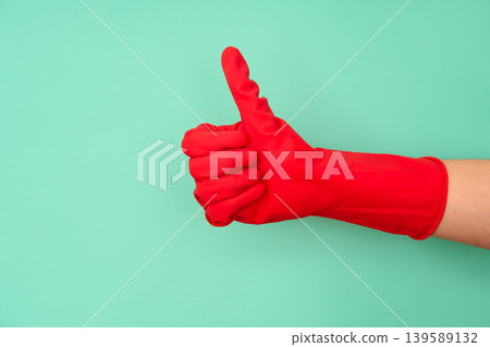 Hand in red cleaning glove thumbs up on teal background 139589132