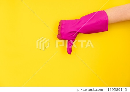 Pink cleaning glove thumbs down on yellow background Pink cleaning glove thumbs down on yellow background 139589143