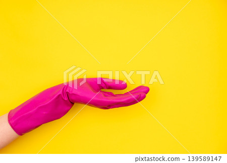 Pink cleaning glove with open palm on yellow 139589147