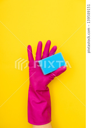 Hand in pink cleaning glove holding blue sponge Hand in pink cleaning glove holding blue sponge 139589151