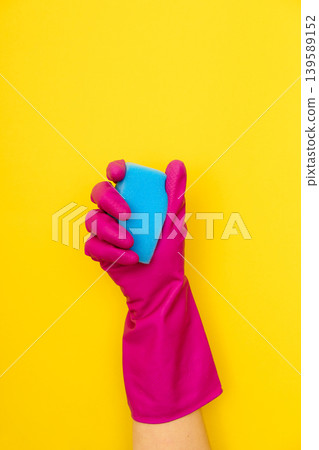 Hand in pink cleaning glove holding blue sponge Hand in pink cleaning glove holding blue sponge 139589152