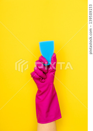 Hand in pink cleaning glove holding blue sponge 139589153