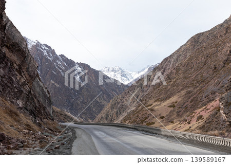 Mountain road through Too Ashuu Pass in Kyrgyzstan with snowy peaks in distance Mountain road through Too Ashuu Pass in Kyrgyzstan with snowy peaks in distance 139589167