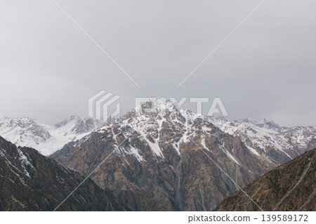 Snowy Tian Shan mountains at Too Ashuu Pass with dramatic cloudy sky, Kyrgyzstan Snowy Tian Shan mountains at Too Ashuu Pass with dramatic cloudy sky, Kyrgyzstan 139589172