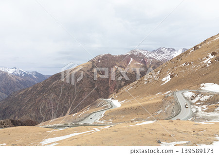 Winding mountain road at Too Ashuu Pass with snowy peaks, Kyrgyzstan 139589173