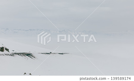 Snowy mountain road at Ala-Bel Pass with winter landscape and distant peaks 139589174