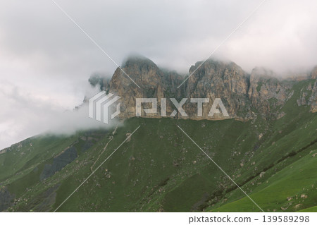 Misty rocky peaks above green slopes near Aktoprak village in the Caucasus Misty rocky peaks above green slopes near Aktoprak village in the Caucasus 139589298