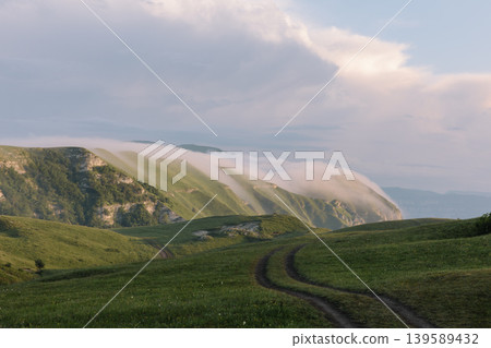 Fog over mountain ridges and dirt road in Dagestan highlands at sunrise 139589432