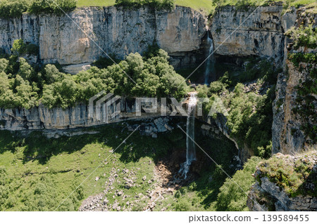 Matlas waterfalls cascading into a rocky canyon with green forest, Dagestan 139589455