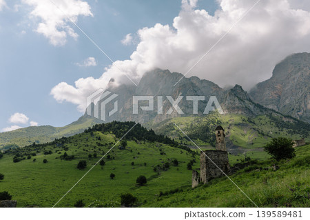 Ancient stone tower ruins in Galgai Gorge with Caucasus mountains and clouds Ancient stone tower ruins in Galgai Gorge with Caucasus mountains and clouds 139589481