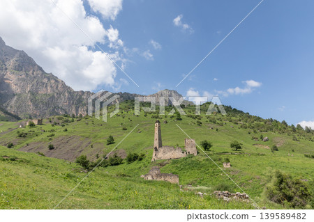 Tower settlement Doshkhakle ruins on green mountain slope under blue sky Tower settlement Doshkhakle ruins on green mountain slope under blue sky 139589482