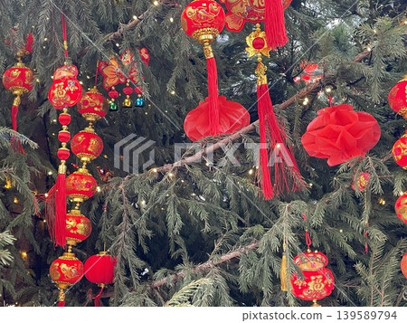 Chinese New Year lanterns hanging on a tree adorned with lights and red decorations 139589794