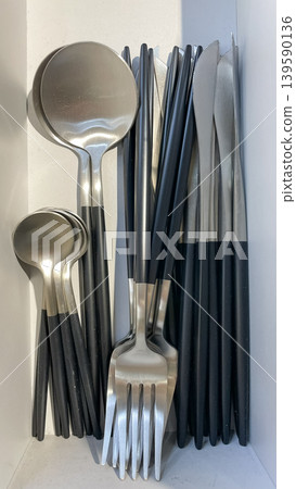 Modern stainless steel cutlery set with matte black handles featuring forks, spoons, and knives in a minimalist arrangement Modern stainless steel cutlery set with matte black handles featuring forks, spoons, and knives in a minimalist arrangement 139590136