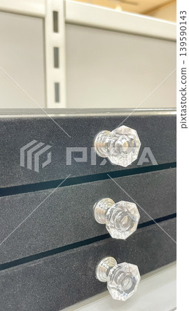 Side view of a dark grey velvet jewelry organizer featuring three drawers with elegant faceted crystal handles Side view of a dark grey velvet jewelry organizer featuring three drawers with elegant faceted crystal handles 139590143