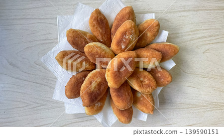 Top view of delicious golden fried pirozhki served on white napkins over a light wooden background 139590151