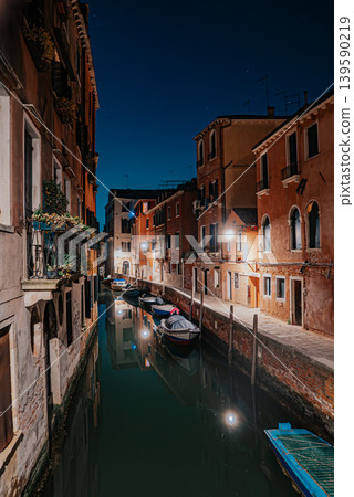 Romantic Venetian canal scene at night with reflections and old buildings Romantic Venetian canal scene at night with reflections and old buildings 139590219