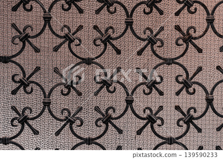 Ornate wrought iron scrollwork pattern on textured glass background 139590233