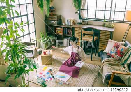 A young Japanese woman painting on the living room floor. A young Japanese woman painting on the living room floor. 139590292