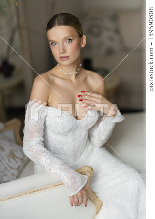 Elegant bride in white long dress posing on chaise lounge Elegant bride in white long dress posing on chaise lounge 139590308