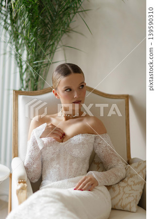 Bride sitting on couch wearing elegant wedding dress Bride sitting on couch wearing elegant wedding dress 139590310