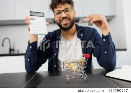 Man calculating home expenses holding house keys Man calculating home expenses holding house keys 139590337