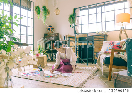 一位年輕的日本女子正在客廳地板上作畫。 一位年輕的日本女子正在客廳地板上作畫。 139590356