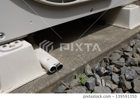 Drain hose of an air conditioner's outdoor unit. White piping and gravel contact surface. Close-up. Drain hose of an air conditioner's outdoor unit. White piping and gravel contact surface. Close-up. 139591350