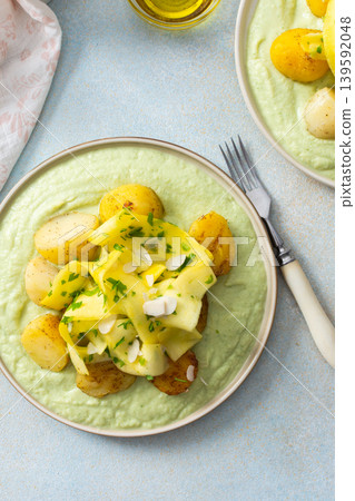 Baked potatoes are topped with fermented zucchini slices and served on a green pea sauce with broccoli for a healthy breakfast option that is hearty Baked potatoes are topped with fermented zucchini slices and served on a green pea sauce with broccoli for a healthy breakfast option that is hearty 139592048