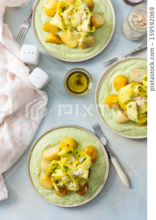 Baked potatoes are topped with slices of fermented zucchini and served alongside a green pea sauce with broccoli. This meal is prepared for a healthy breakfast Baked potatoes are topped with slices of fermented zucchini and served alongside a green pea sauce with broccoli. This meal is prepared for a healthy breakfast 139592069