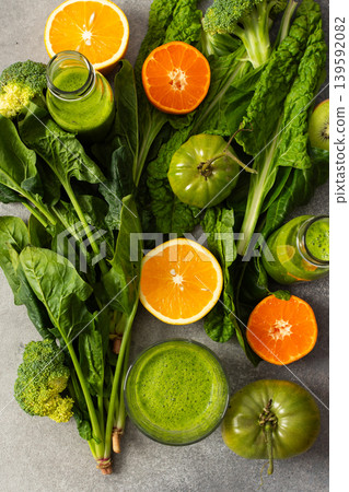 Juice is being made from fresh greens like spinach, chard, and broccoli along with oranges and tangerines. The process takes place in summer with bright colors and natural ingredients Juice is being made from fresh greens like spinach, chard, and broccoli along with oranges and tangerines. The process takes place in summer with bright colors and natural ingredients 139592082