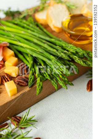 Indulge in a beautifully arranged charcuterie board with vibrant asparagus, savory cured meats, assorted cheeses, and freshly toasted bread, ideal for sharing with friends Indulge in a beautifully arranged charcuterie board with vibrant asparagus, savory cured meats, assorted cheeses, and freshly toasted bread, ideal for sharing with friends 139592352