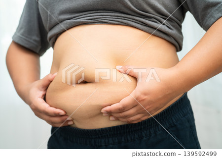 Asian woman use hand to squeeze fat belly big size overweight and obesity. Asian woman use hand to squeeze fat belly big size overweight and obesity. 139592499