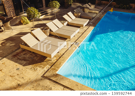 Swimming pool with empty lounge chairs at luxury resort on sunny day Swimming pool with empty lounge chairs at luxury resort on sunny day 139592744