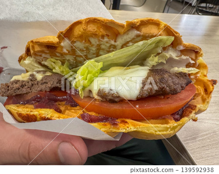 Viennese waffle cheeseburger with beef patty, melted cheese, lettuce and tomato, gourmet fast food sandwich close-up Viennese waffle cheeseburger with beef patty, melted cheese, lettuce and tomato, gourmet fast food sandwich close-up 139592938