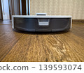 White robot vacuum cleaner on wooden floor, smart home cleaning device close-up in modern apartment interior 139593074