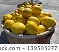 Ripe yellow lemons in a wicker basket, fresh citrus display at an open market under the sun 139593077