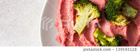 A nutritious, filling breakfast featuring beetroot hummus and steamed broccoli, perfect for a healthy start to the day, banner 139593128