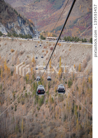 Cable car gondolas moving over autumn mountain forest in Shymbulak, Kazakhstan. Cable car gondolas moving over autumn mountain forest in Shymbulak, Kazakhstan. 139593457