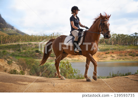 Equestrian, woman and riding a horse in nature on adventure and journey in countryside. Ranch, animal and rider outdoor with hobby, sport or walking a pet on farm with girl in summer at river Equestrian, woman and riding a horse in nature on adventure and journey in countryside. Ranch, animal and rider outdoor with hobby, sport or walking a pet on farm with girl in summer at river 139593735