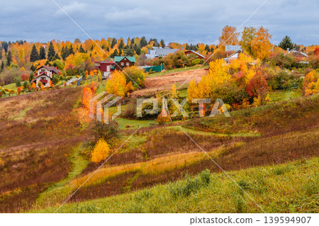 Autumn landscape with colorful foliage and small village in the distance Autumn landscape with colorful foliage and small village in the distance 139594907