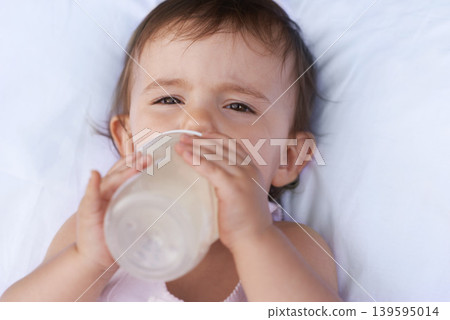 Baby, portrait and drinking milk for nutrition, liquid food and relax on bed at home. Girl, toddler and formula for health or child development in bedroom, feeding and bottle for wellness and growth Baby, portrait and drinking milk for nutrition, liquid food and relax on bed at home. Girl, toddler and formula for health or child development in bedroom, feeding and bottle for wellness and growth 139595014