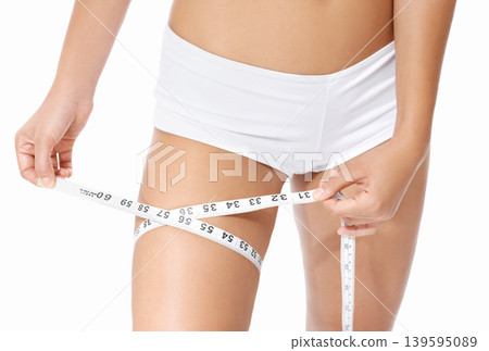 Woman, legs and tape measure for diet, weight loss or slim body in health and wellness on a white studio background. Closeup of female person or model hands measuring thigh in fitness or healthcare Woman, legs and tape measure for diet, weight loss or slim body in health and wellness on a white studio background. Closeup of female person or model hands measuring thigh in fitness or healthcare 139595089