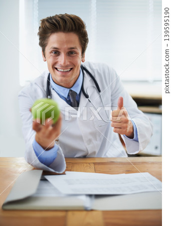 Thumbs up, apple and portrait of man doctor with stethoscope for positive, good and confident attitude. Happy, smile and young healthcare worker with fruit in medical office of hospital or clinic. Thumbs up, apple and portrait of man doctor with stethoscope for positive, good and confident attitude. Happy, smile and young healthcare worker with fruit in medical office of hospital or clinic. 139595190